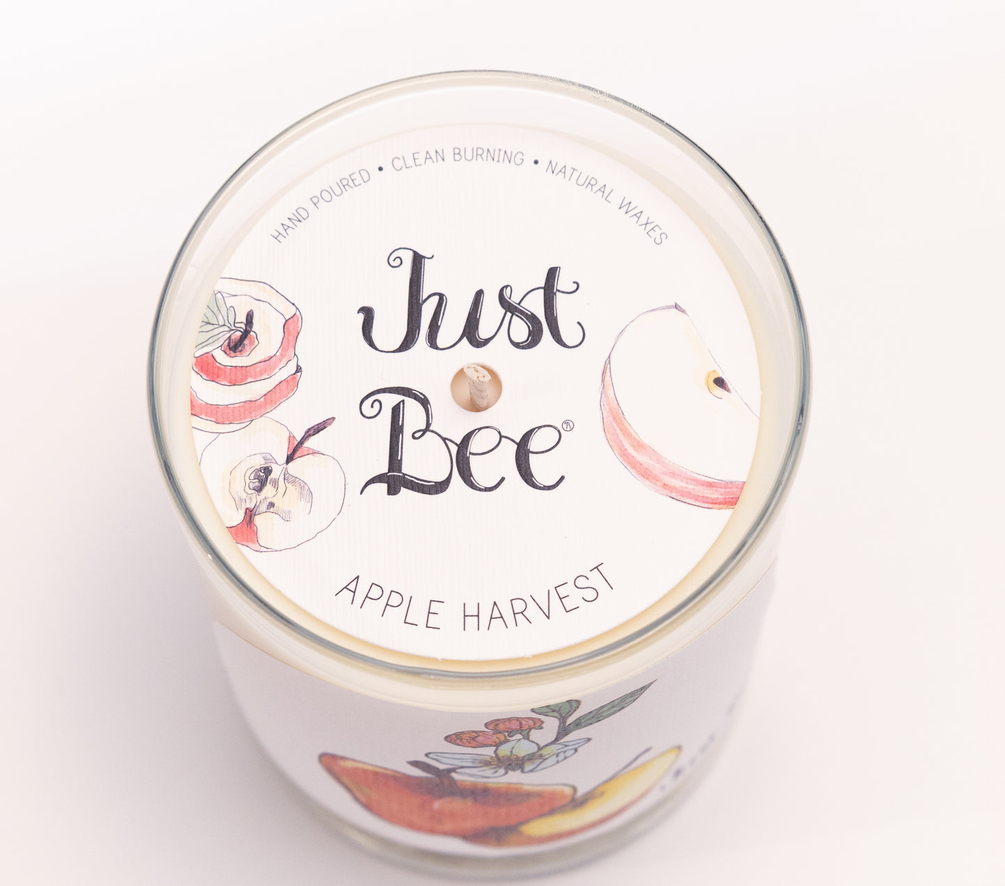 Just Bee Apple Harvest candle from above, round lid label with sliced apples and a centered wick.