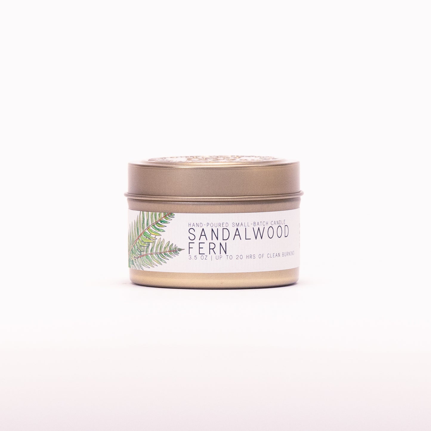 Just Bee Sandalwood Fern candle in a closed gold travel tin, fern frond label facing forward.