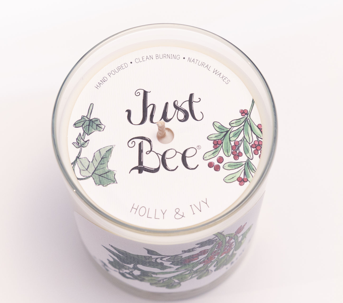 Just Bee Holly & Ivy candle from above, round lid label with holly berries and a centered wick.