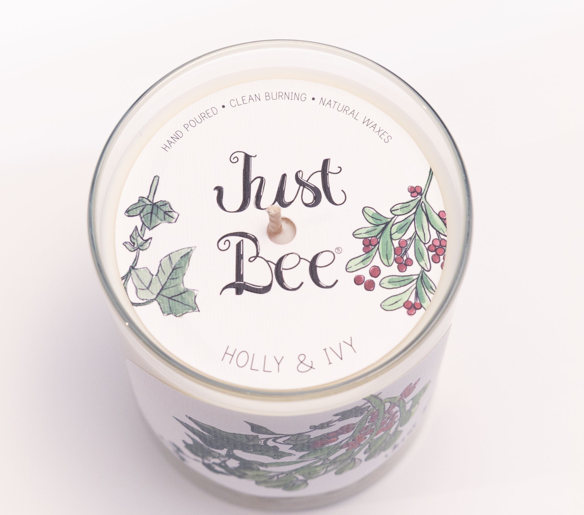 Just Bee Holly & Ivy candle from above, round lid label with holly berries and a centered wick.