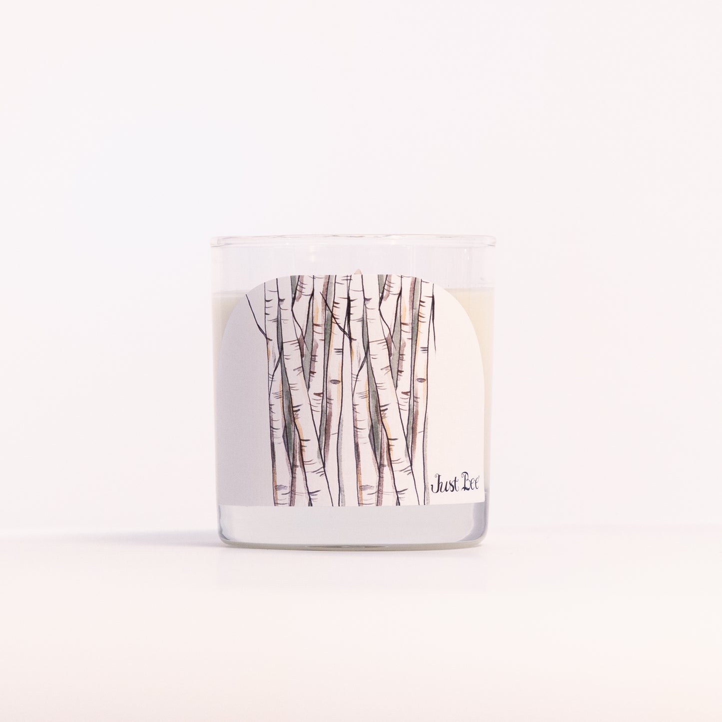 Just Bee White Birch candle in a clear glass jar, birch trunk label facing forward in a closer view.