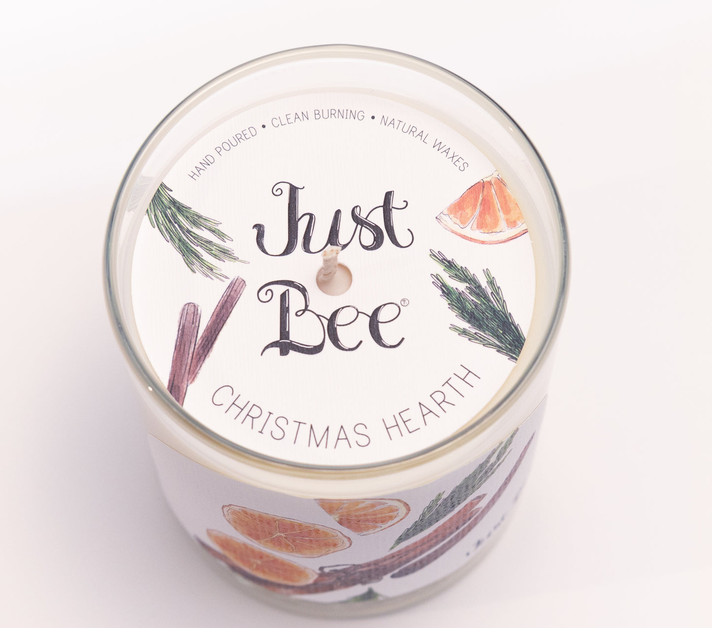 Just Bee Christmas Hearth candle from above, round lid label with orange slices, pine and a centered wick.
