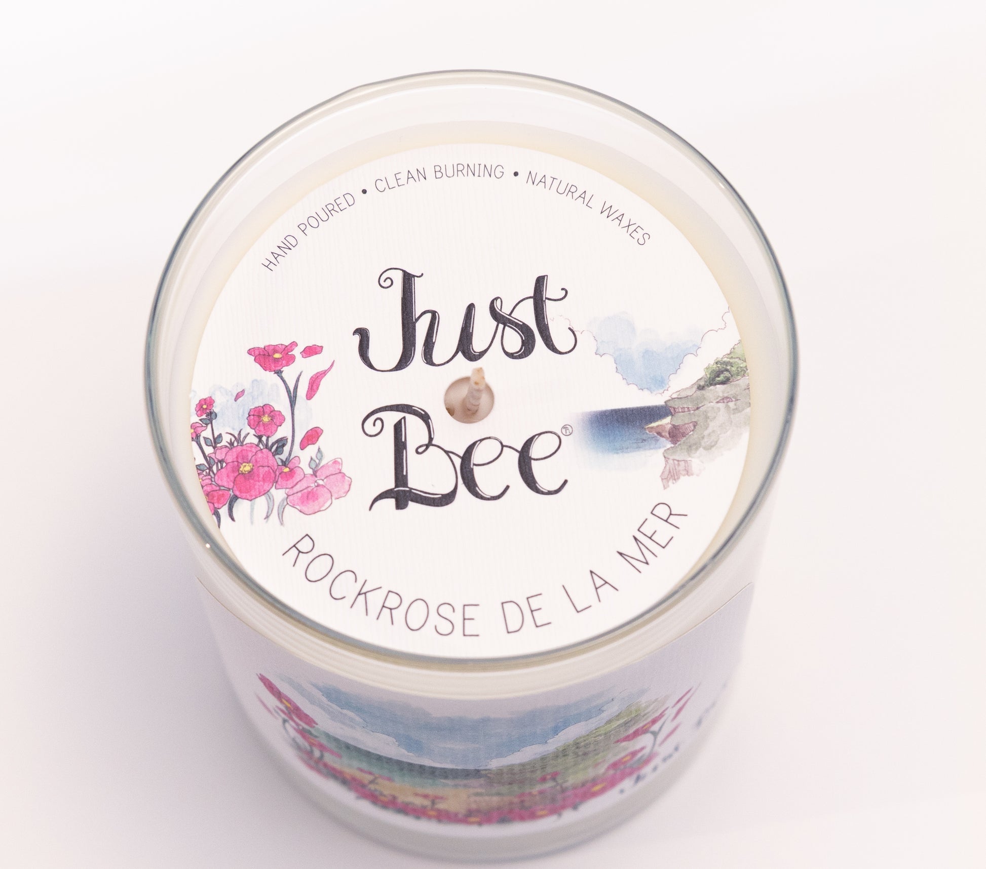 Just Bee Rockrose de la Mer candle from above, round lid label with pink rockrose and a centered wick.