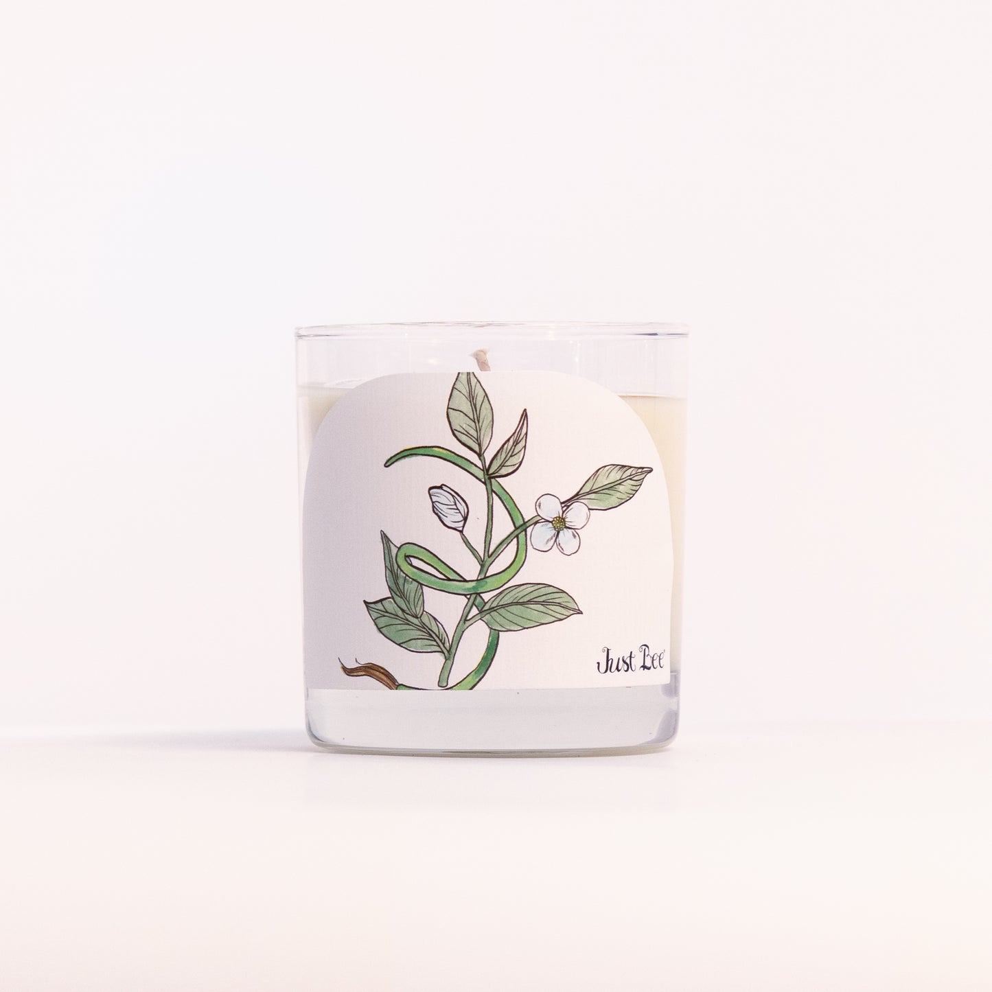 Just Bee Black Tea & Vetiver candle in a clear glass jar, tea leaf label facing forward in a closer view.