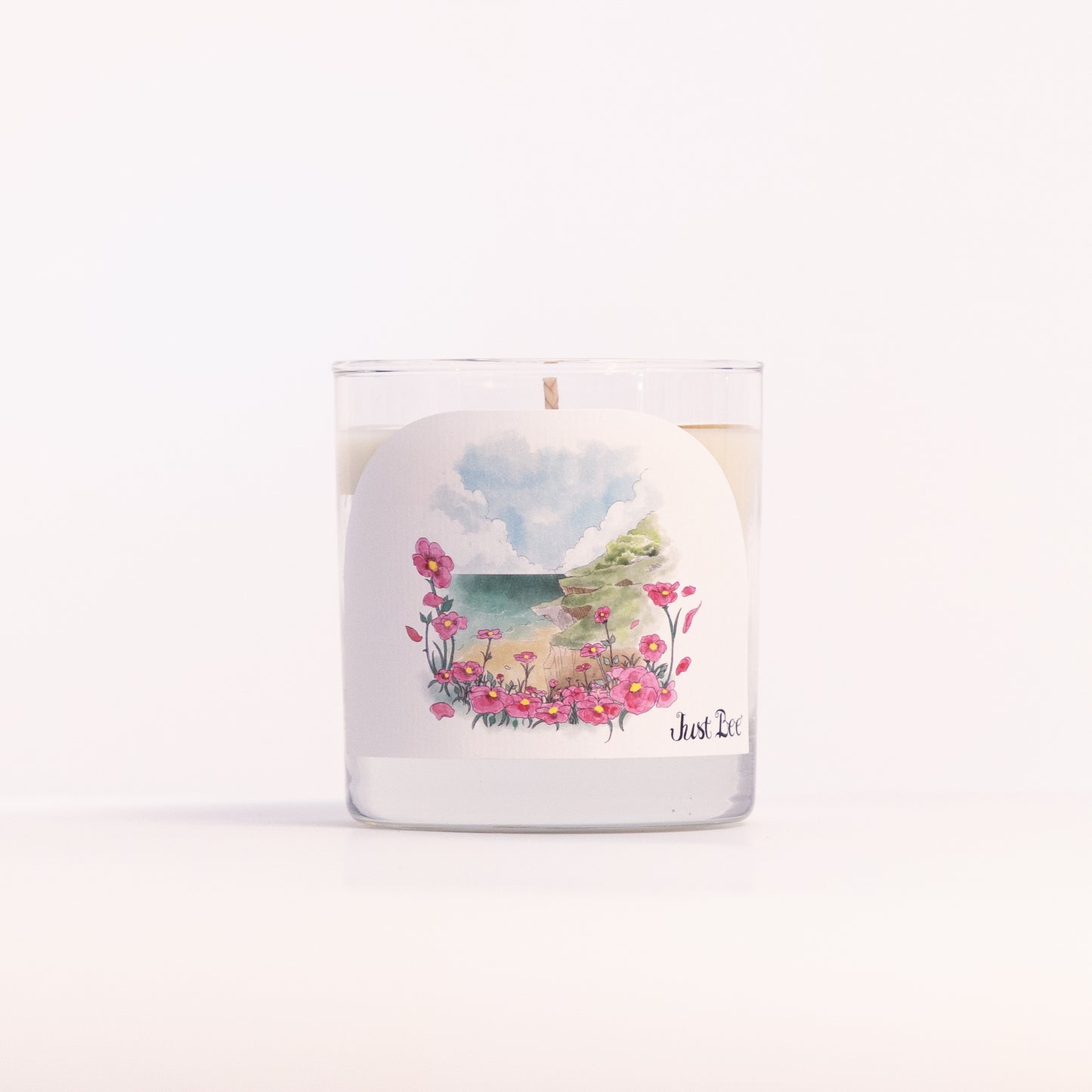 Just Bee Rockrose de la Mer candle in a clear glass jar, coastal rockrose label facing forward, closer view.