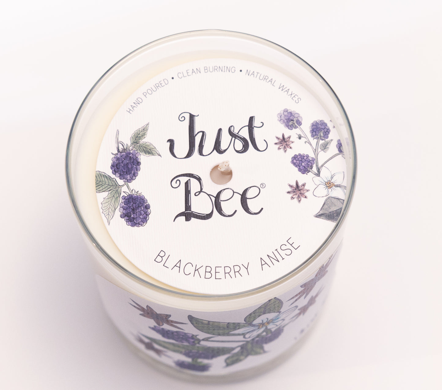 Just Bee Blackberry Anise candle from above, round lid label with blackberries and a centered wick.