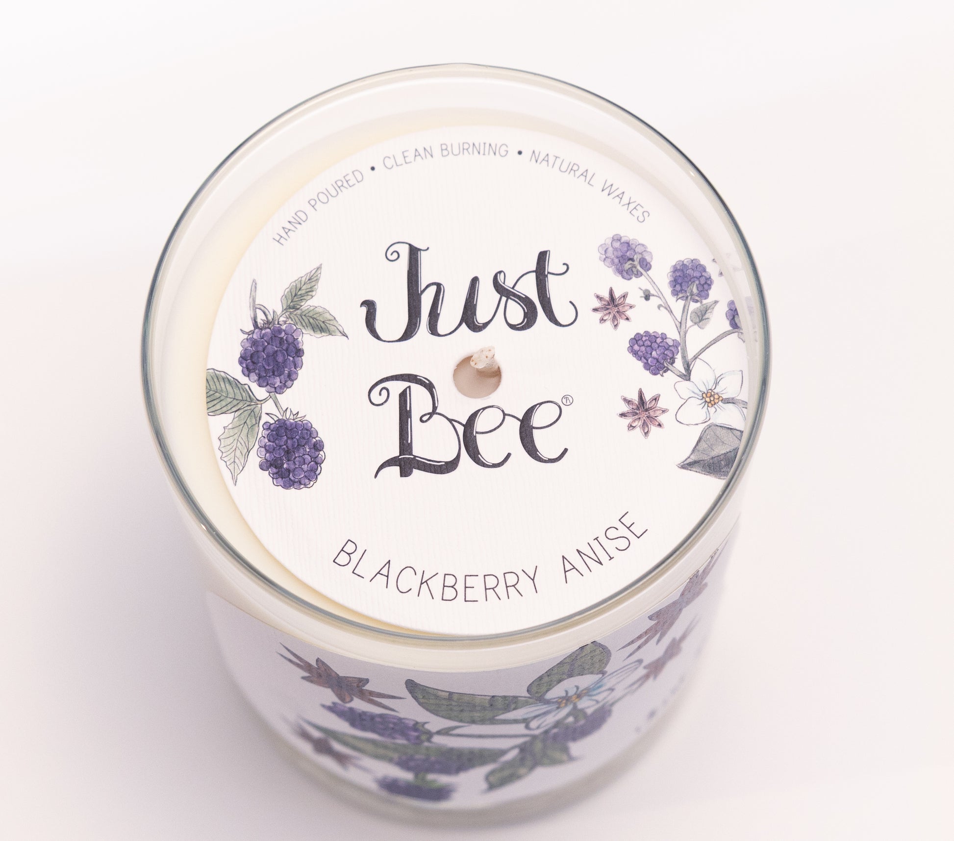 Just Bee Blackberry Anise candle from above, round lid label with blackberries and a centered wick.