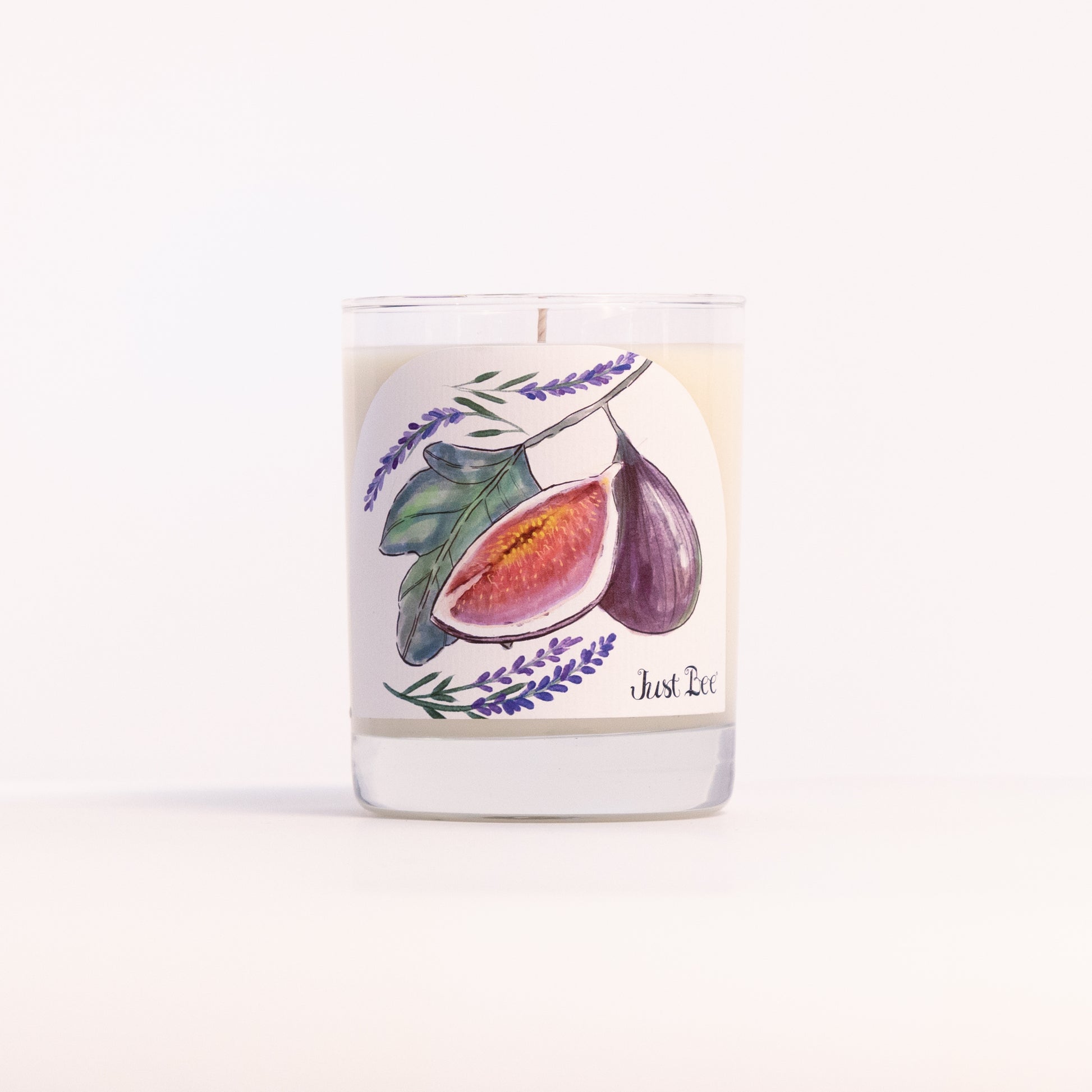 Just Bee Lavender Fig candle in a clear glass jar illustrated with halved purple figs and lavender.