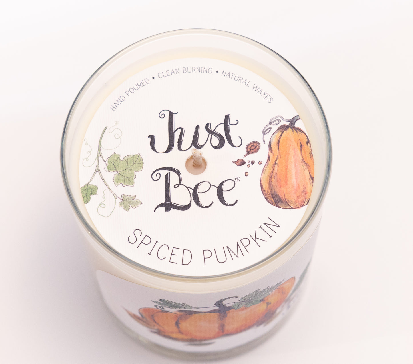 Just Bee Spiced Pumpkin candle from above, round lid label with pumpkins, vines and a centered wick.