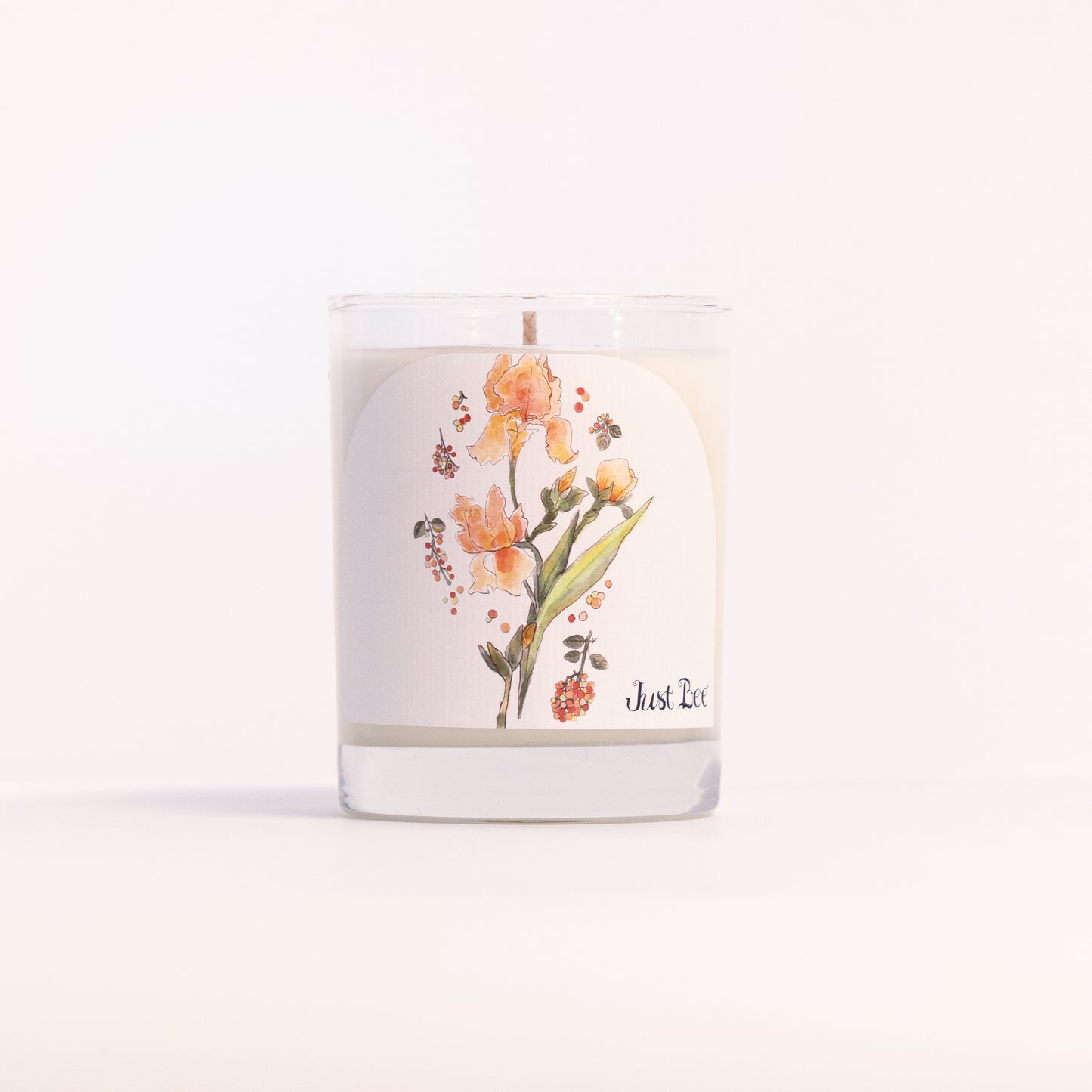 Just Bee Iris & Pink Peppercorn candle in a clear glass jar illustrated with orange iris blooms.