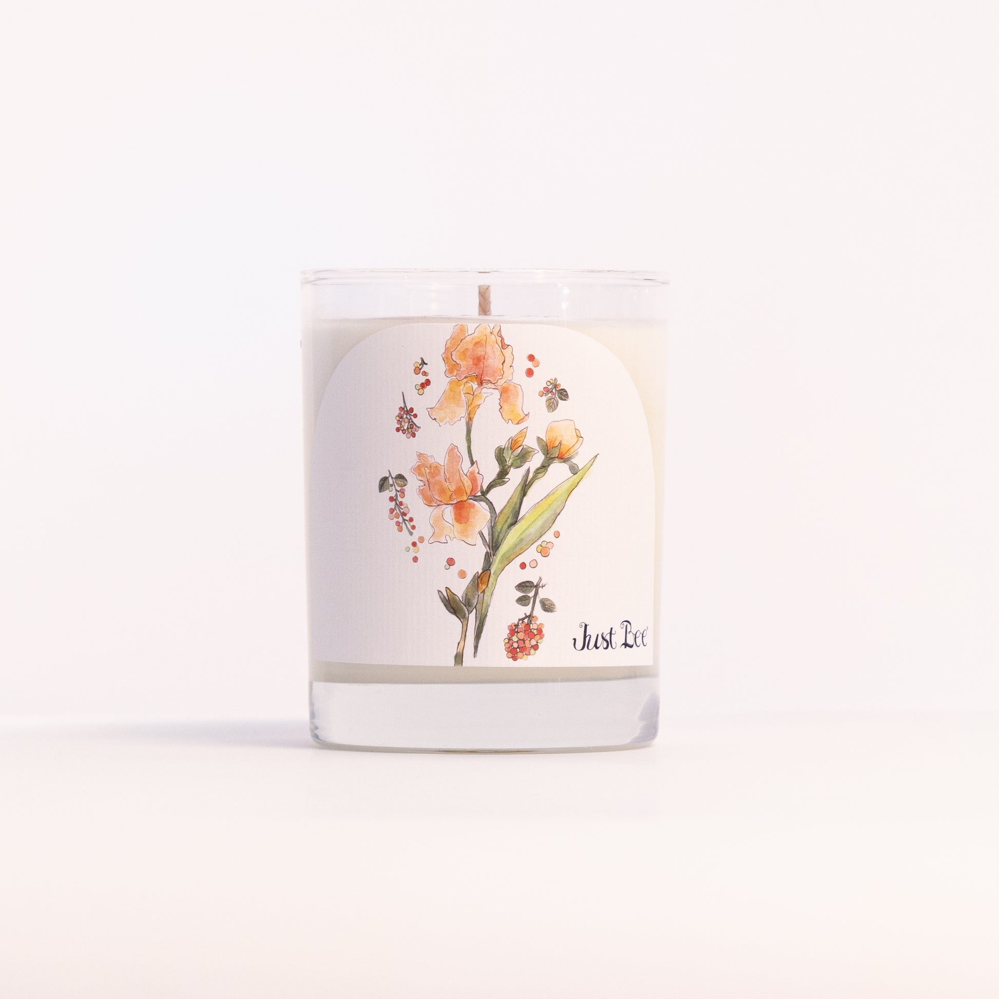 Just Bee Iris & Pink Peppercorn candle in a clear glass jar illustrated with orange iris blooms.