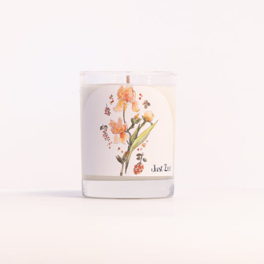 Just Bee Iris & Pink Peppercorn candle in a clear glass jar illustrated with orange iris blooms.
