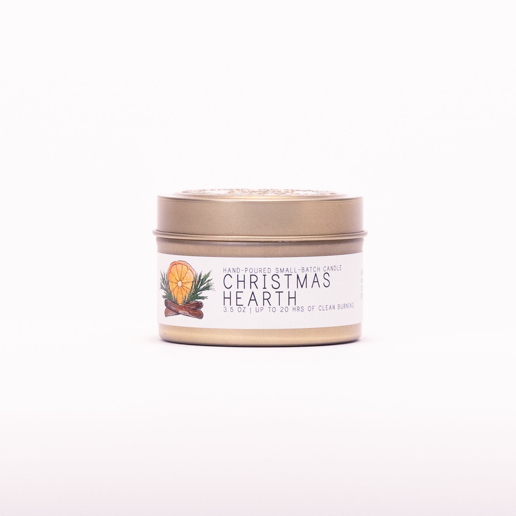 Just Bee Christmas Hearth candle in a closed gold travel tin, orange and cinnamon label facing forward.