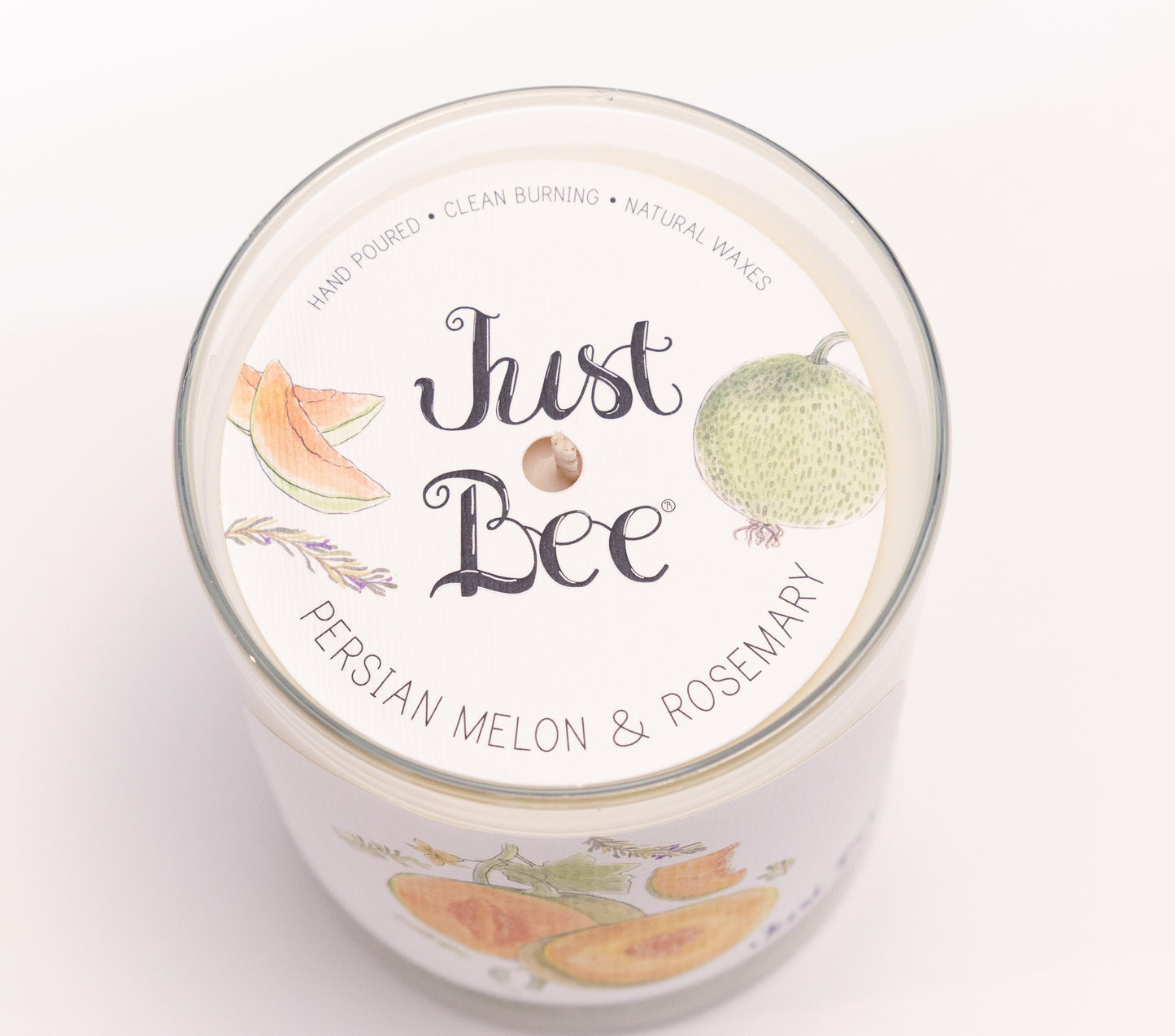 Just Bee Persian Melon & Rosemary candle from above, round lid label with melon slices and a centered wick.