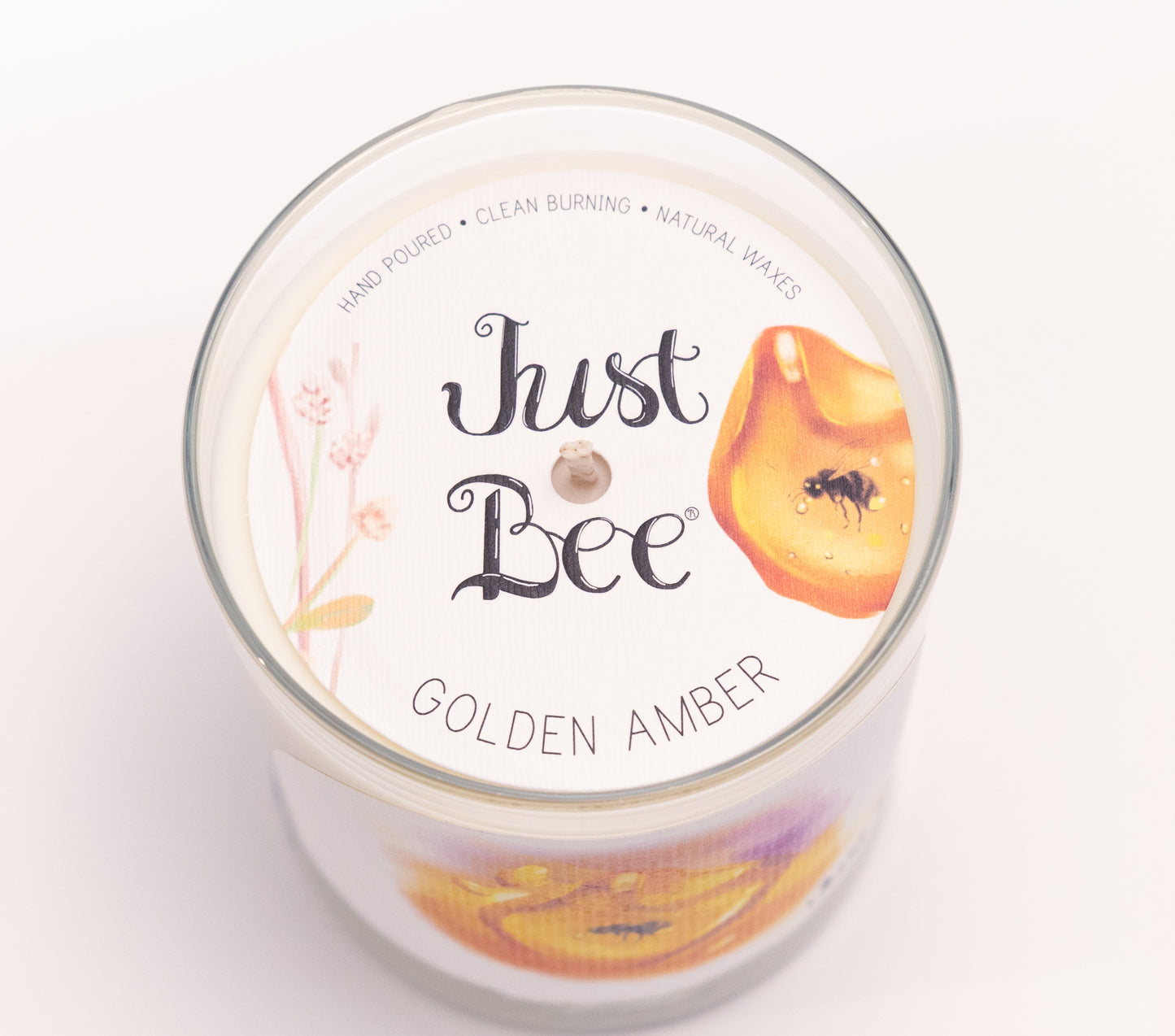 Just Bee Golden Amber candle from above, round lid label with amber resin, a bee and a centered wick.