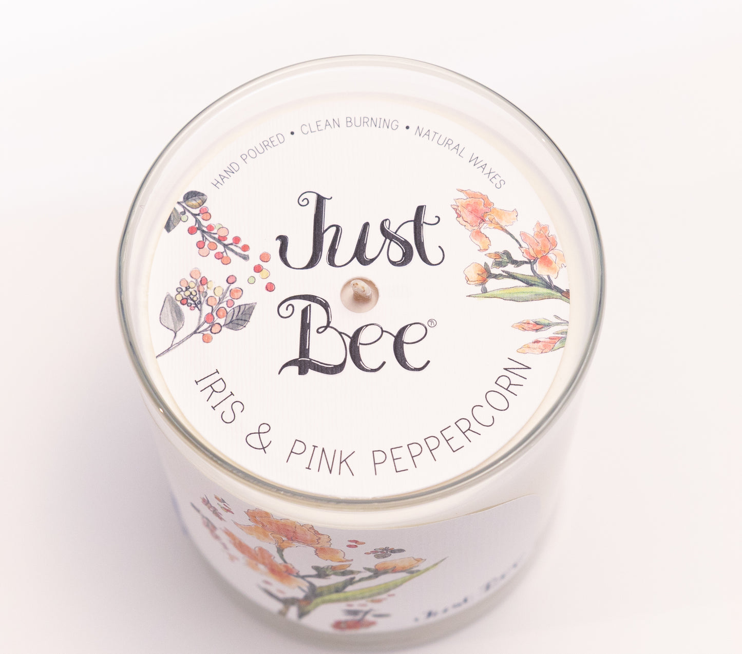 Just Bee Iris & Pink Peppercorn candle from above, round lid label with iris blooms and a centered wick.