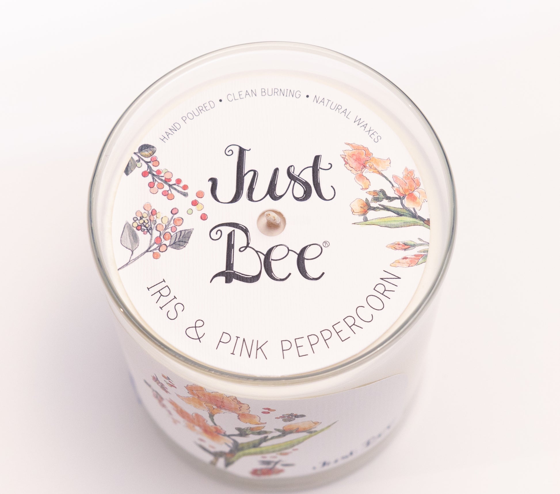 Just Bee Iris & Pink Peppercorn candle from above, round lid label with iris blooms and a centered wick.