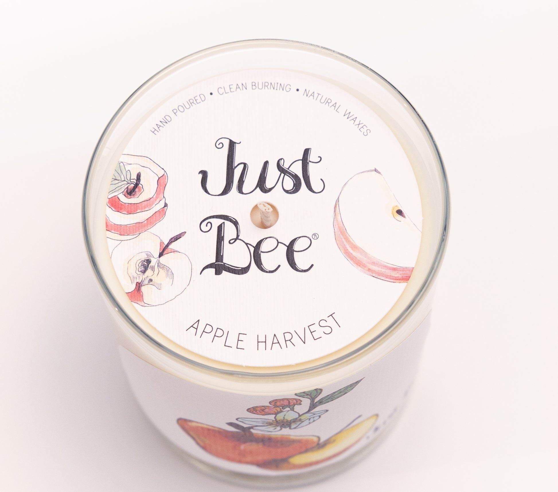 Just Bee Apple Harvest candle from above, round lid label with sliced apples and a centered wick.