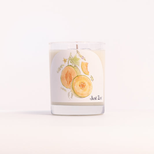 Just Bee Persian Melon & Rosemary candle in a clear glass jar illustrated with melon slices and rosemary.