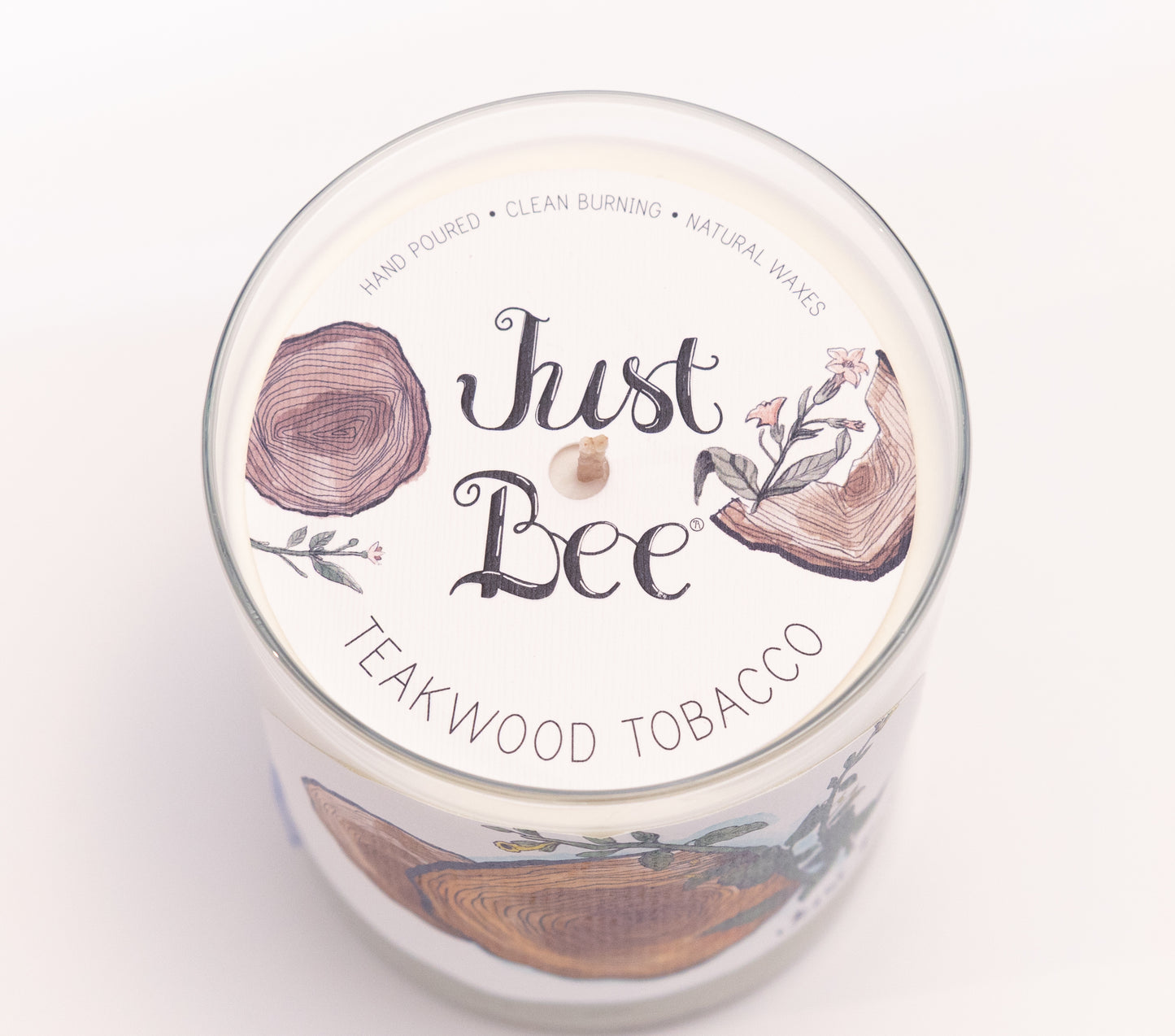 Just Bee Teakwood Tobacco candle from above, round lid label with a tree ring motif and centered wick.