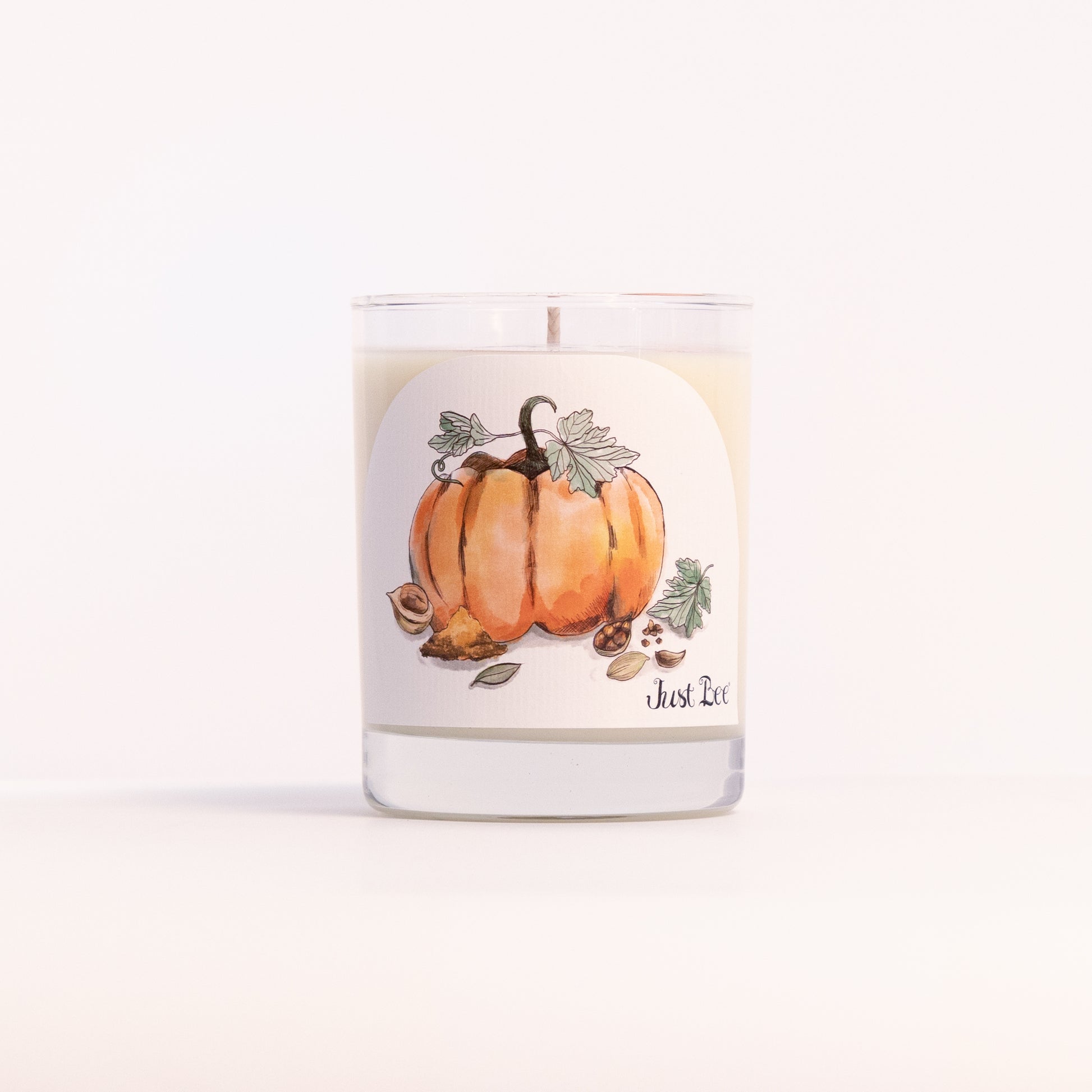 Just Bee Spiced Pumpkin candle in a clear glass jar illustrated with orange pumpkins, vines and leaves.
