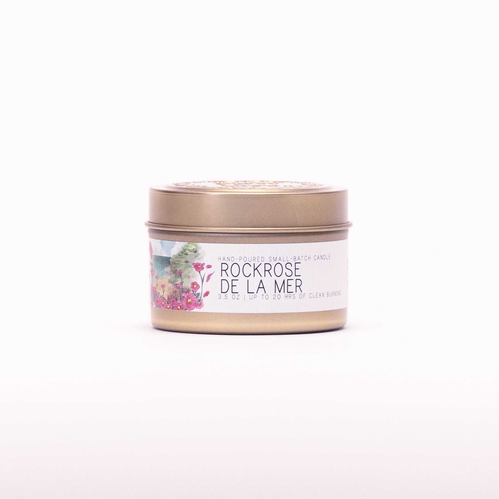Just Bee Rockrose de la Mer candle in a closed gold travel tin, pink rockrose label facing forward.