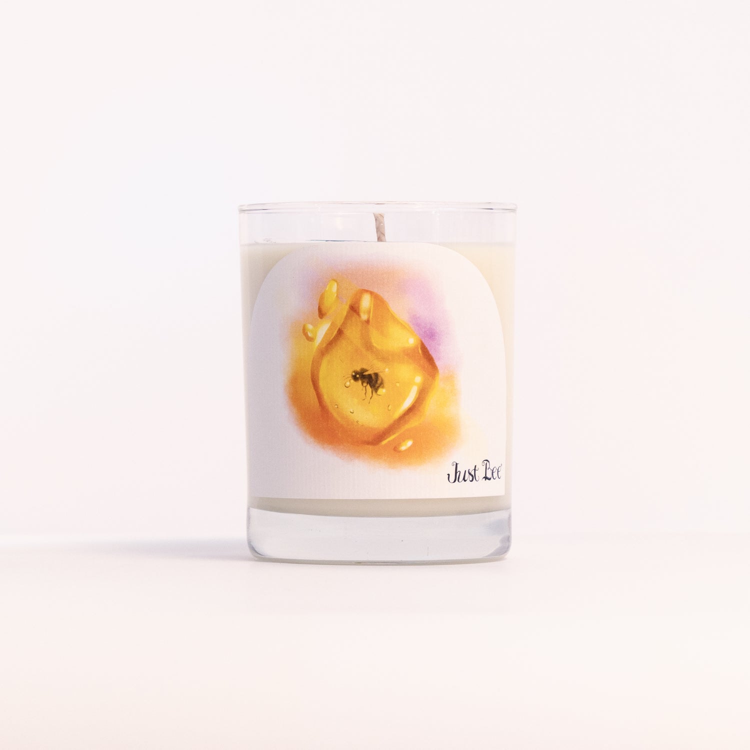 Just Bee Golden Amber candle in a clear glass jar illustrated with a golden amber resin drop and a bee.