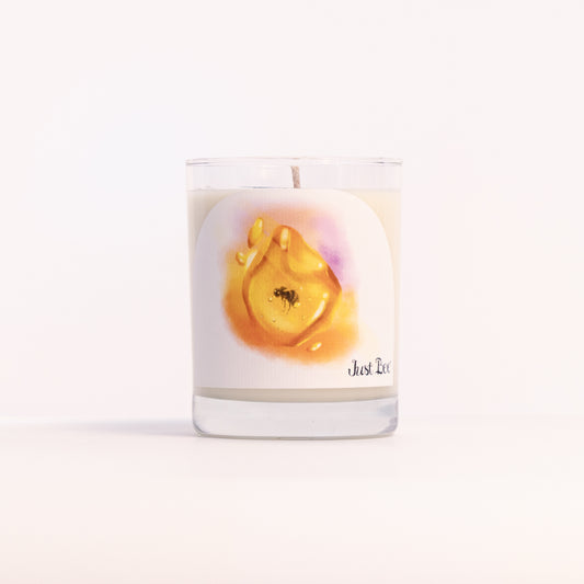 Just Bee Golden Amber candle in a clear glass jar illustrated with a golden amber resin drop and a bee.