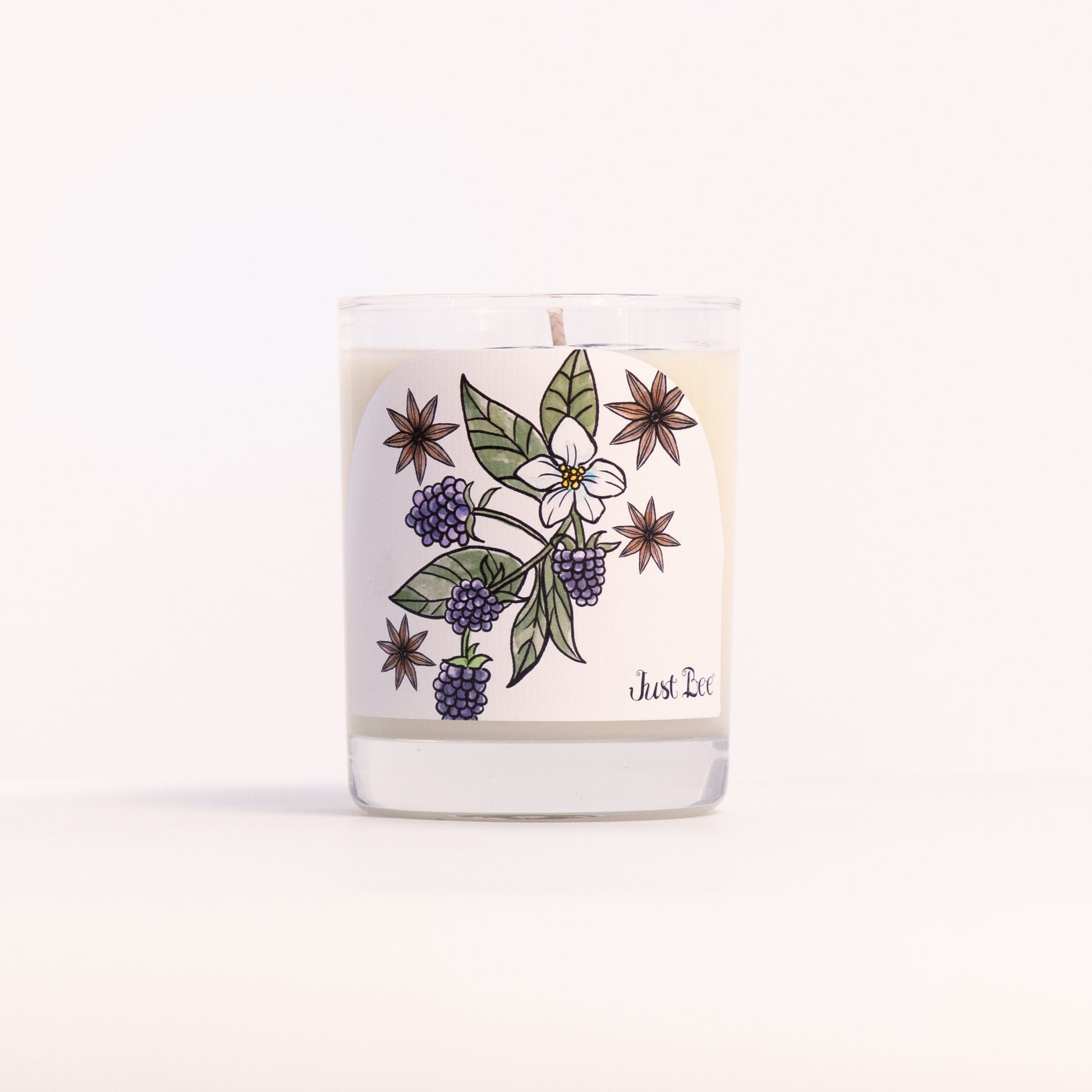Just Bee Blackberry Anise candle in a clear glass jar illustrated with blackberries and star anise.