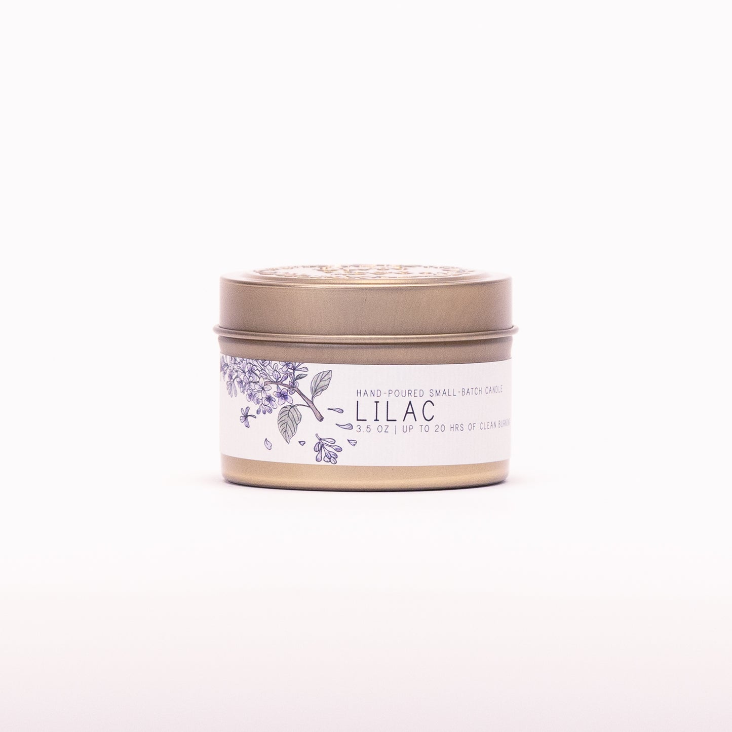 Just Bee Lilac candle in a closed gold travel tin, purple lilac label facing forward.