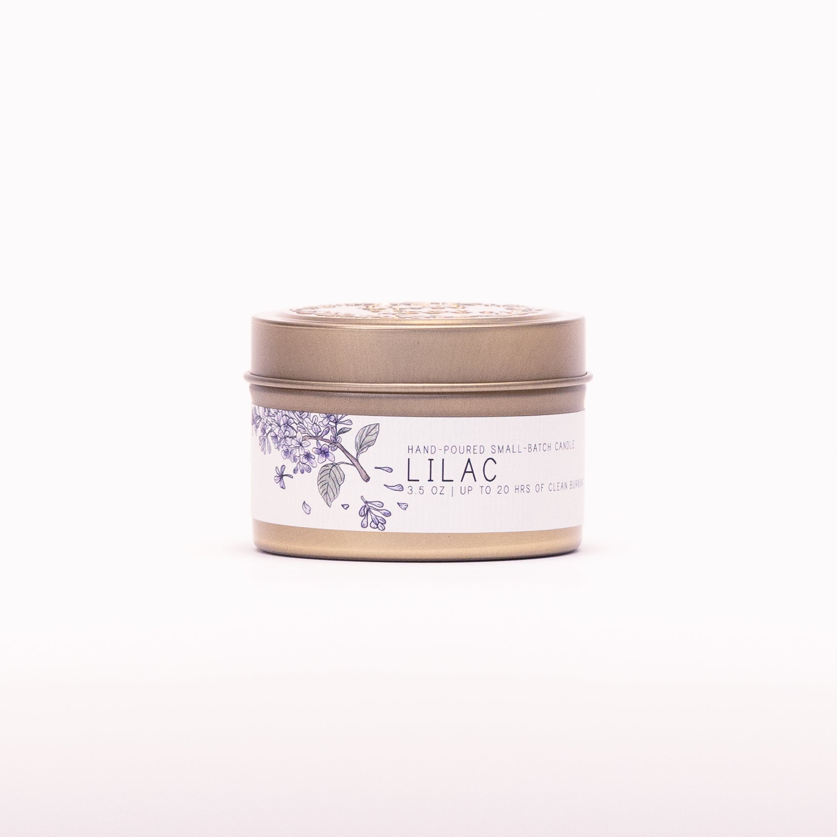 Just Bee Lilac candle in a closed gold travel tin, purple lilac label facing forward.