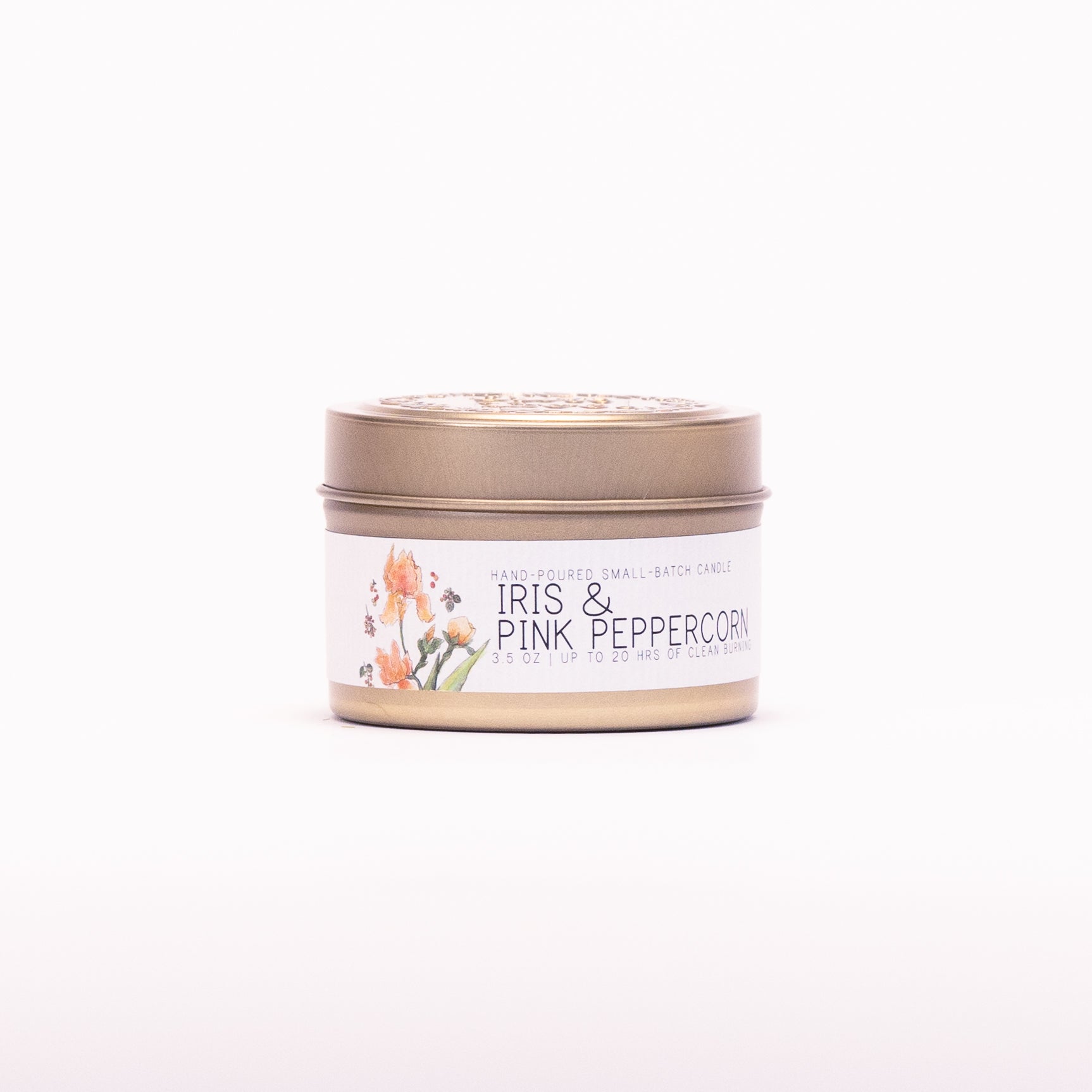 Just Bee Iris & Pink Peppercorn candle in a closed gold travel tin, iris label facing forward.