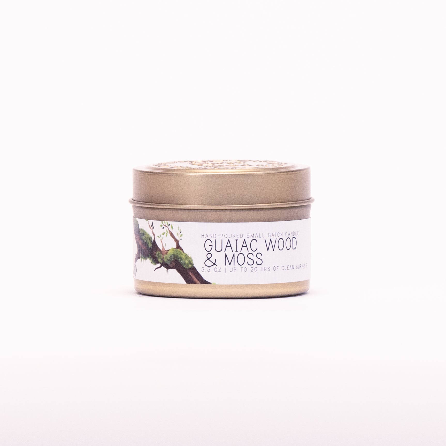Just Bee Guaiac Wood & Moss candle in a closed gold travel tin, mossy branch label facing forward.