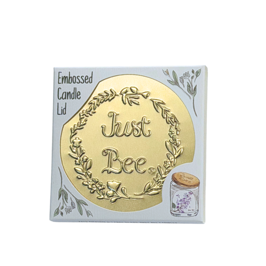 Gold embossed candle lid with the text 'Just Bee' surrounded by floral designs.
